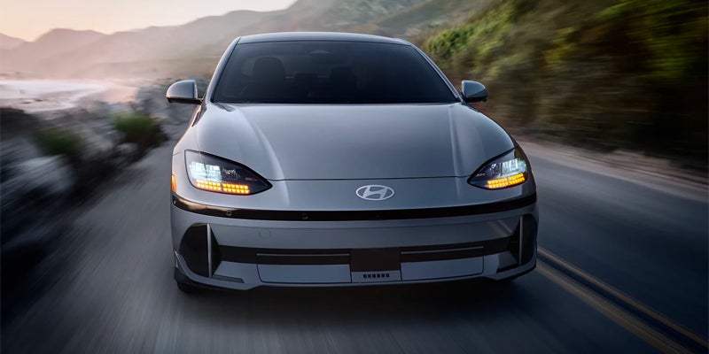 Silver electric sedan driving on highway front view