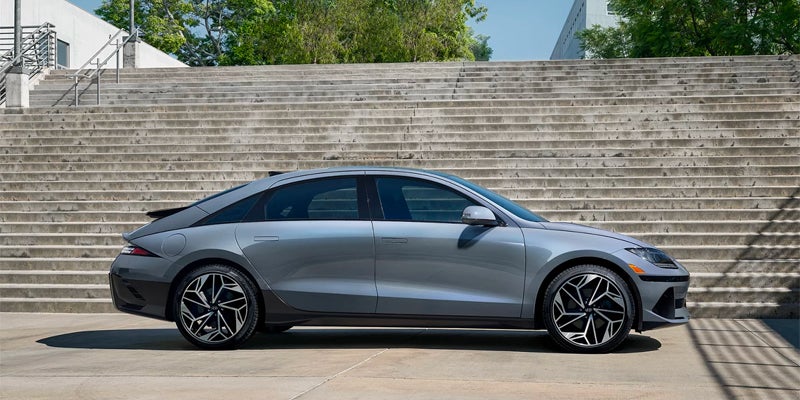 Silver electric sedan side profile against modern wall