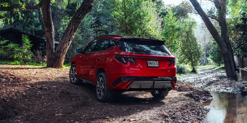 Hyundai Tucson SUV rear view parked beside forest stream